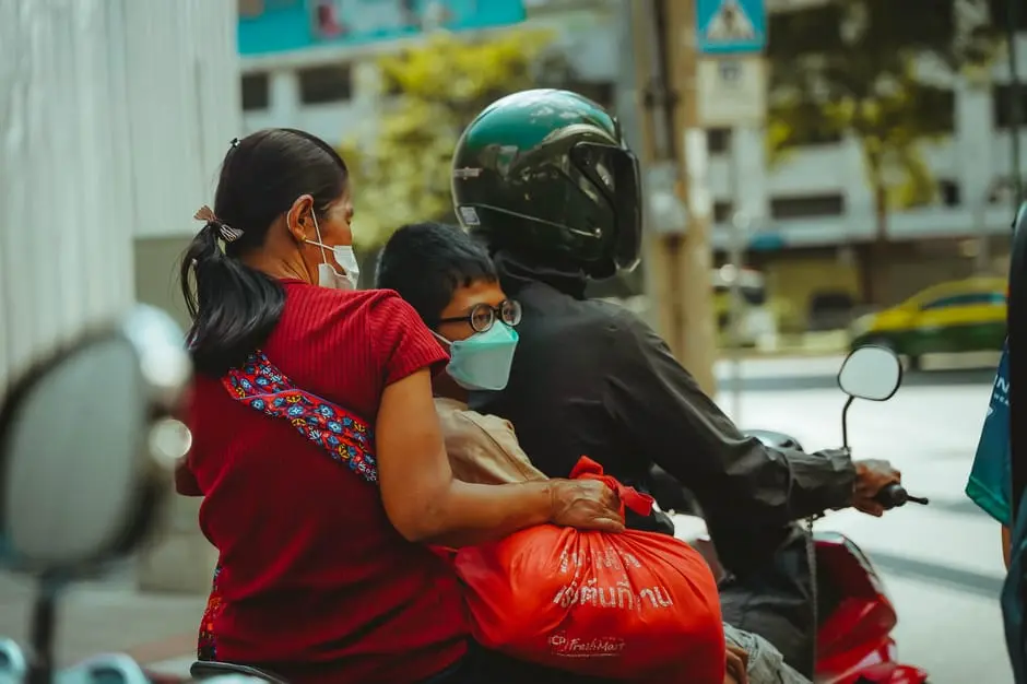 A Family Of Three Rides A Motor Scooter Through The Streets Of Bangkok