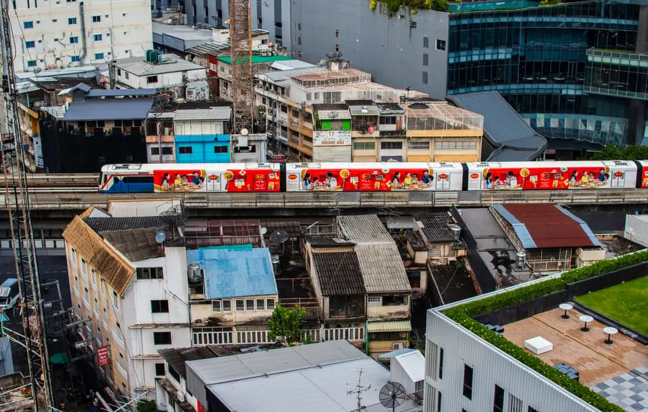 Aerial View Of Bangkok City With A Vibrant Train Passing Through Urban
