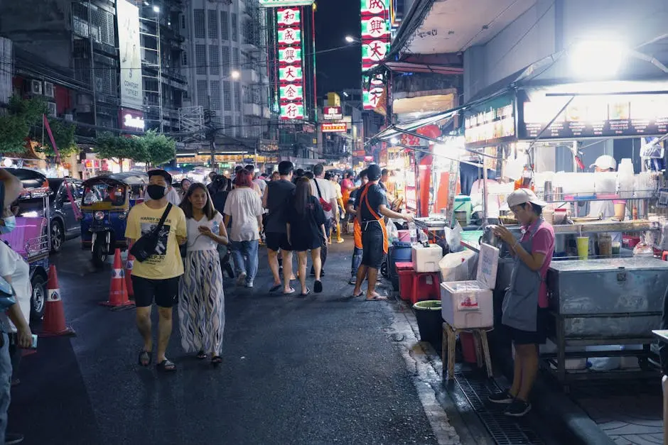 Bustling City Street Market At Night With Food Stalls And People In Vi