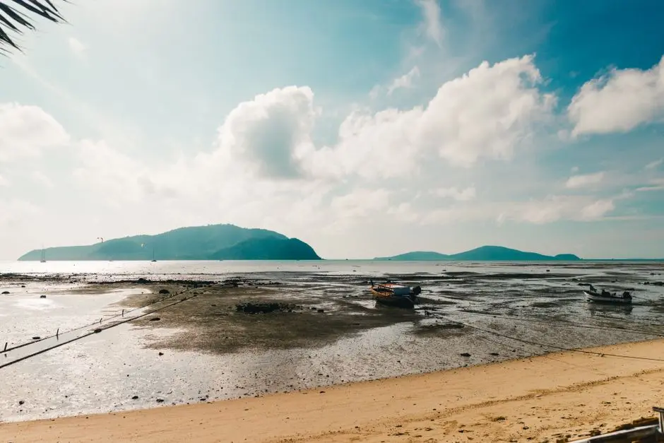 Scenic View Of A Tranquil Beach In Phuket Thailand With Boats And Moun