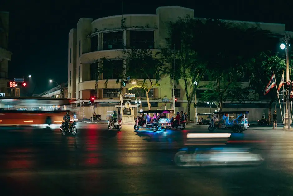 Vibrant City Nightlife Featuring Tuk Tuks And Motorcycles On A Busy St